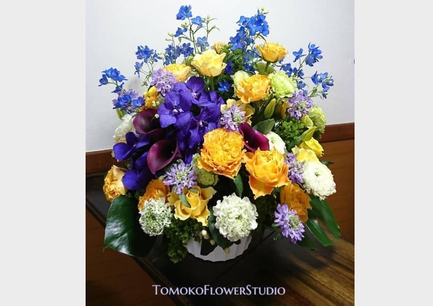 黄色と白のバラ、薄紫の松虫草、濃いボルドーのカラー、ブルーと紫の小花のアレンジ、お届け用